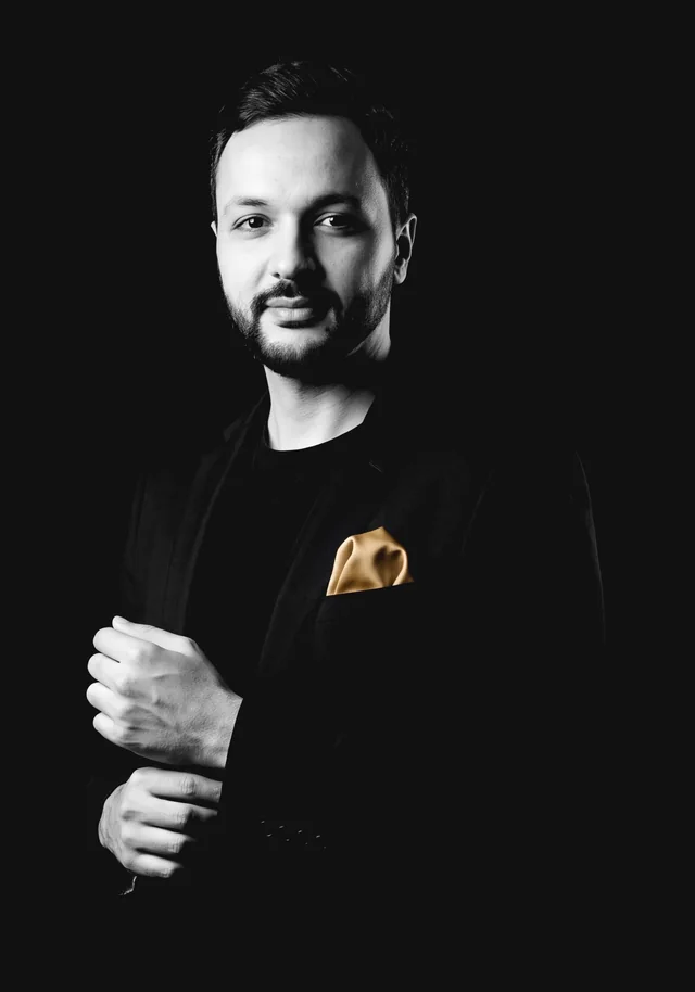 Portrait d’Abdelhamid ZAIM, architecte DE, en veste noire, ajustant sa manchette