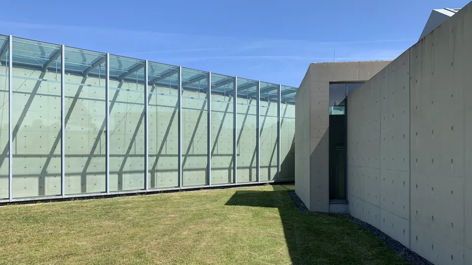 Image d’illustration : mur en béton et galerie vitrée sous un ciel bleu